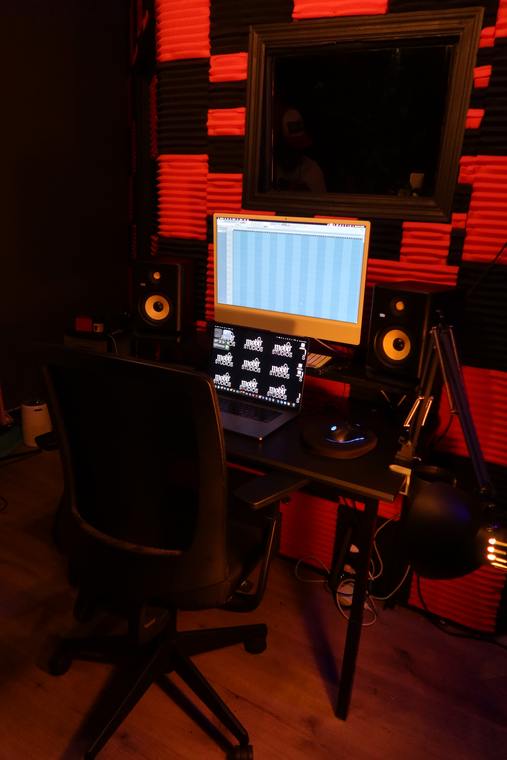 Room B desk with monitors, iMac and laptop against the red foam wall